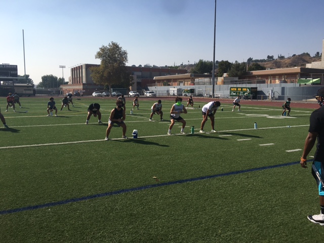 The football team stretches before conditioning while following the Covid-19 regulations set by the Hart District.