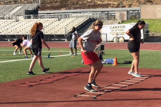 The girls basketball team doing ladders to work on their speed, while maintaining a social distance.
