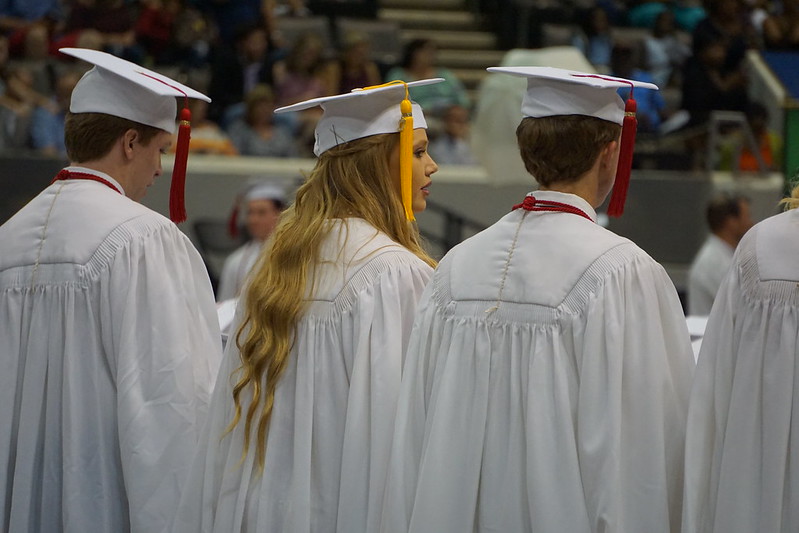 Three high school seniors wait anxiously to receive their diploma (The ancient in-person graduation).