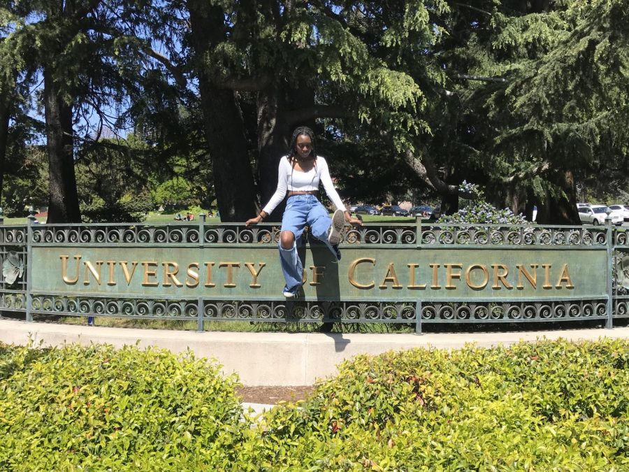 A candid moment of graduating senior, Zara Koroma, sitting on the gate outside UC Berkeley