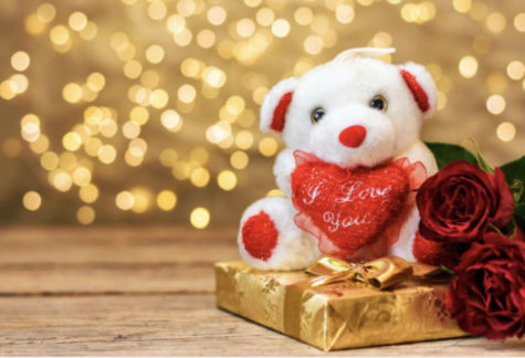 Valentine’s day concept. White plush toy bear, red roses and gift box, on wooden blackboard with copy space for text. Selective focus.