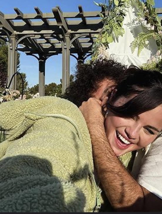 A photo of Benny Blanco and Selena Gomez smiling while hugging each other. 