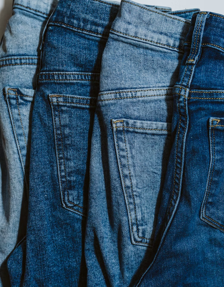 A line of different colored low rise jeans. 