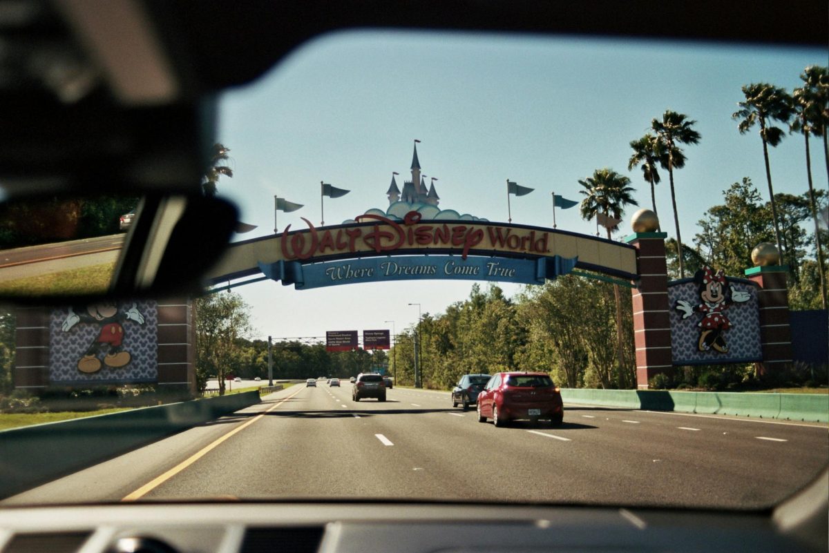 Photo cars driving into the  entrance of Disney World. 